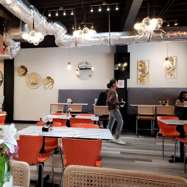 The interior of Scrum-did-dly-ump-tious restaurant with orange chairs and a person walking.