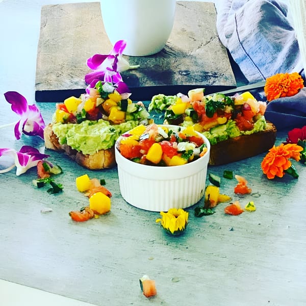 Avocado toast with mango salsa and orchids, a vibrant breakfast from Scrum-did-dly-ump-tious.